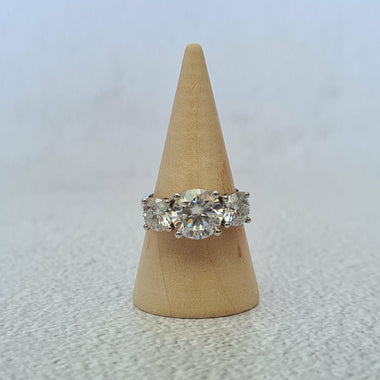 White gold round three stone moissanite engagement ring on wooden cone
