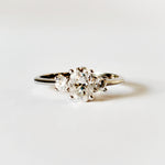 Oval and round cut moissanite three stone engagement ring in white gold, front view on white background