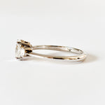 Oval and round cut moissanite three stone engagement ring in white gold, side view on white background
