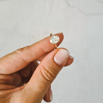 2ct oval moissanite solitaire engagement ring in 9ct yellow gold held between two fingers for size comparison