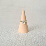 2ct oval moissanite solitaire engagement ring in 9ct yellow gold on a wood cone and grey background