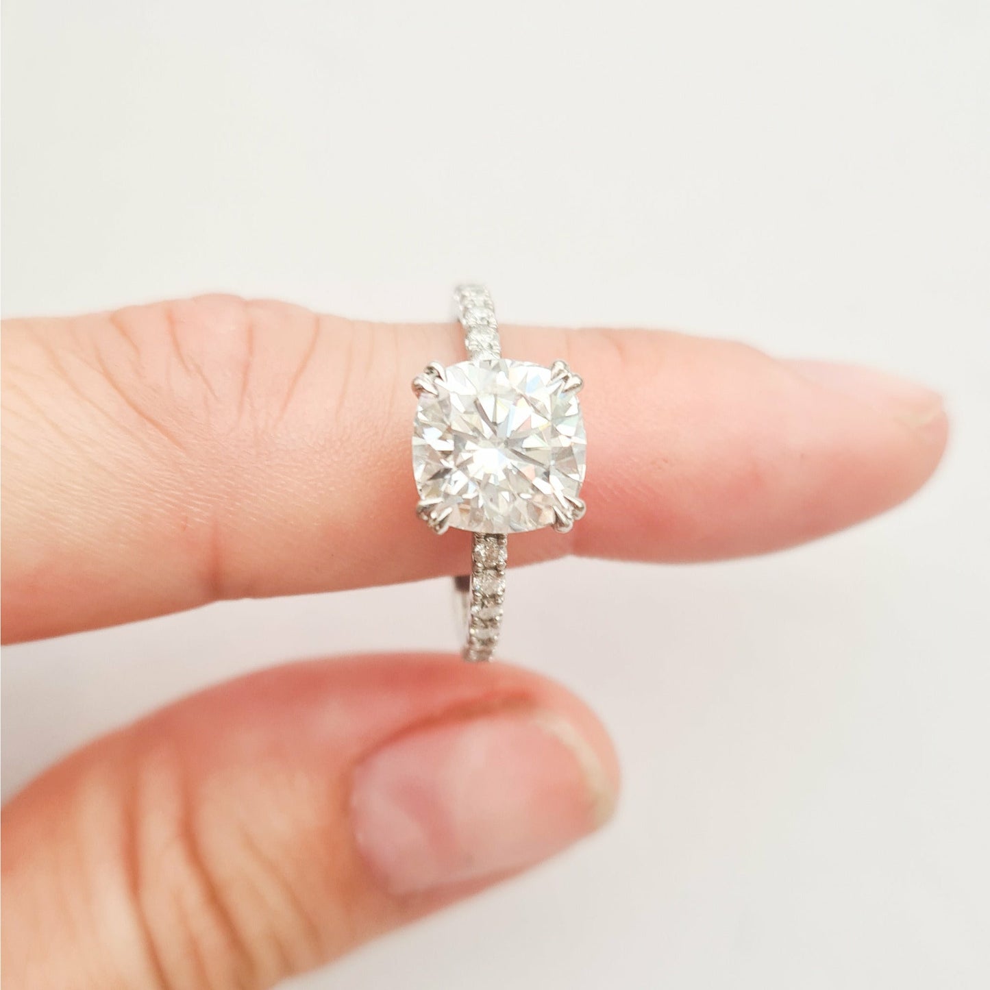 Square cushion cut moissanite engagement ring with double claws on a micropave band